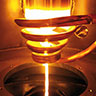 Arcast Gas Atomizer melting a titanium rod. The melt stream drops through the gas jet and is atomized